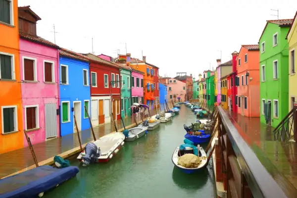 Venise : une maison colorée et d'autres maisons aux teintes vives bordent un canal où flottent des bateaux.