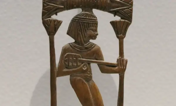 Sculpture en bois d'un musicien égyptien jouant d'un instrument ancien, ornée de motifs floraux.