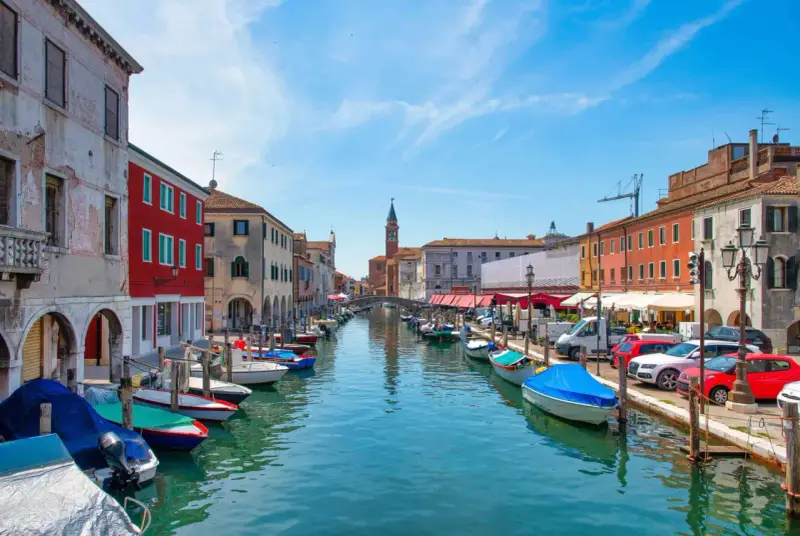 Vue d'un canal à Chioggia, Venise, avec des bateaux amarrés le long des maisons colorées.
